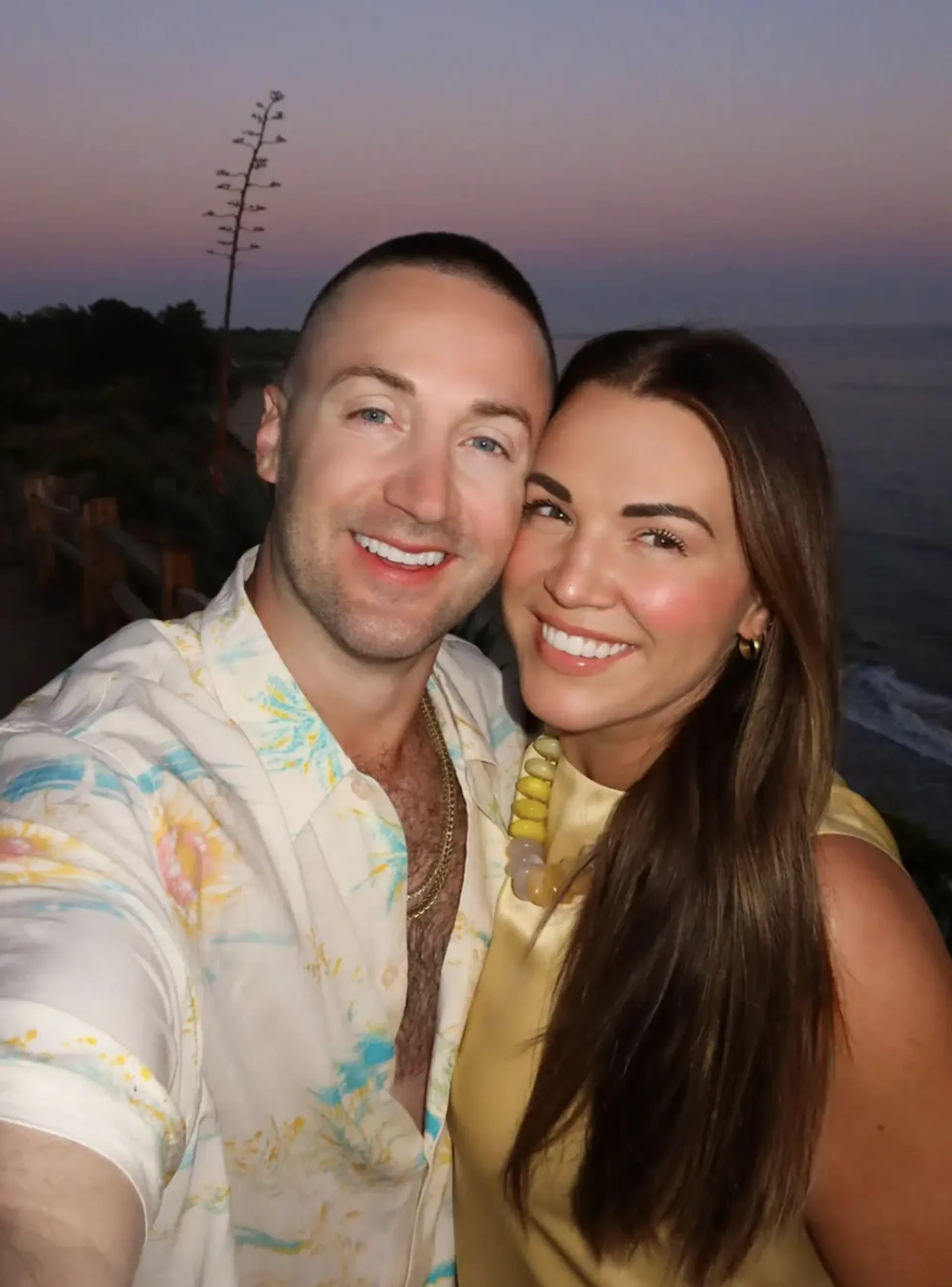 Sarah and Robbie Tripp taking a selfie by the beach at sunset