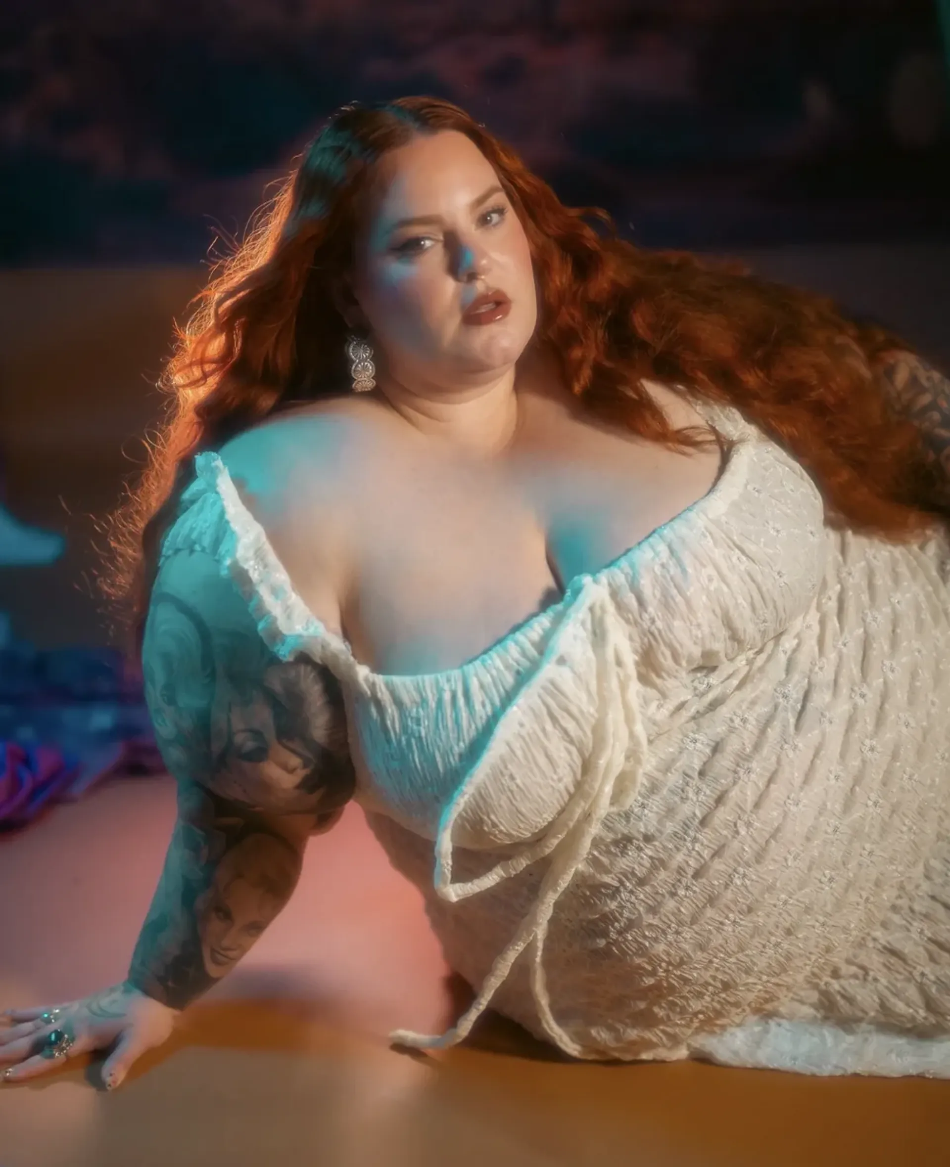 Tess Holliday posing in a white off-shoulder dress