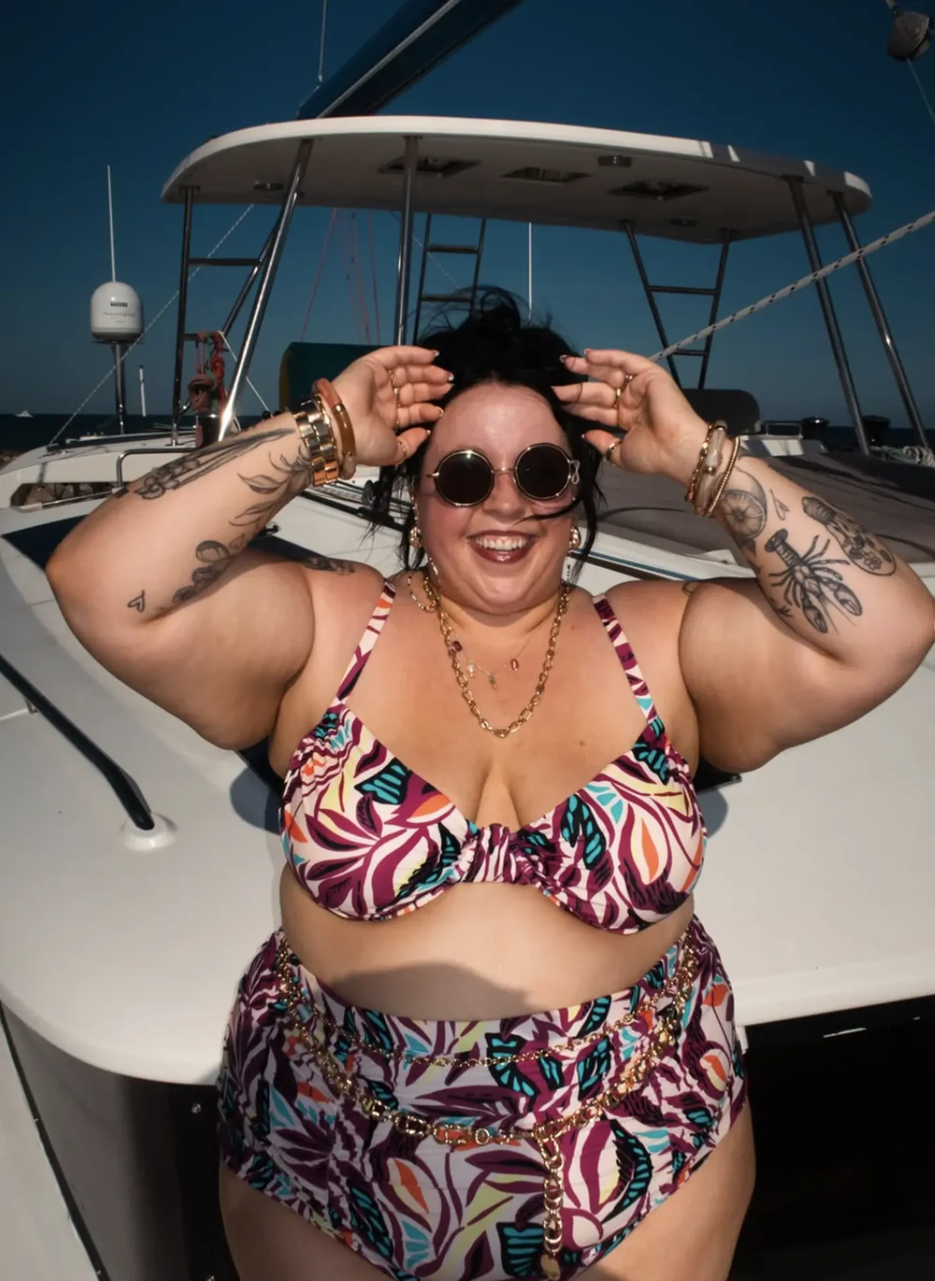 Alicia Mccarvell posing confidently in a colorful bikini on a yacht