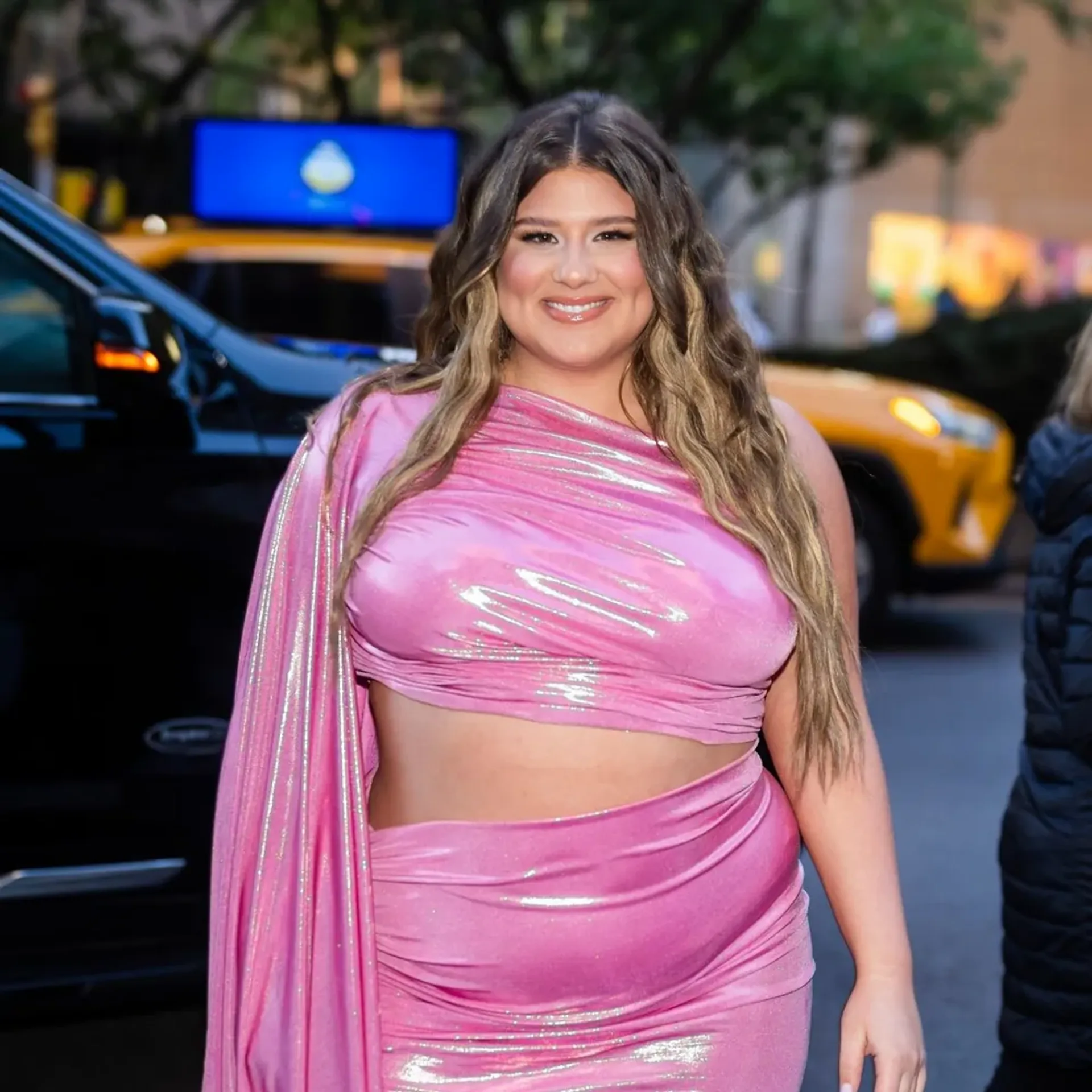 Remi Bader wearing a bright pink two-piece outfit in the city